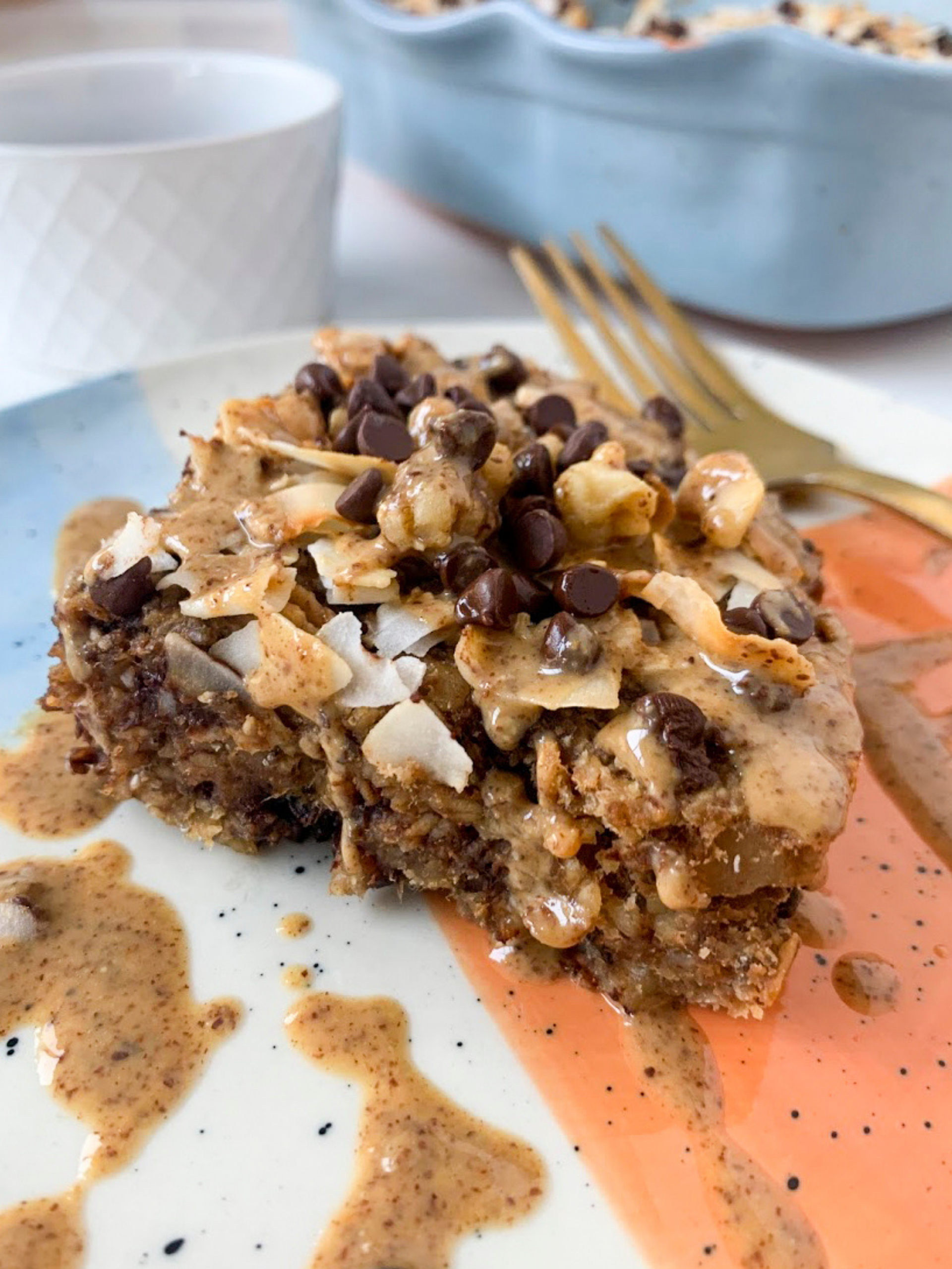 baked oatmeal with chocolate chips, coconut flakes, and almond butter on a plate with a fork