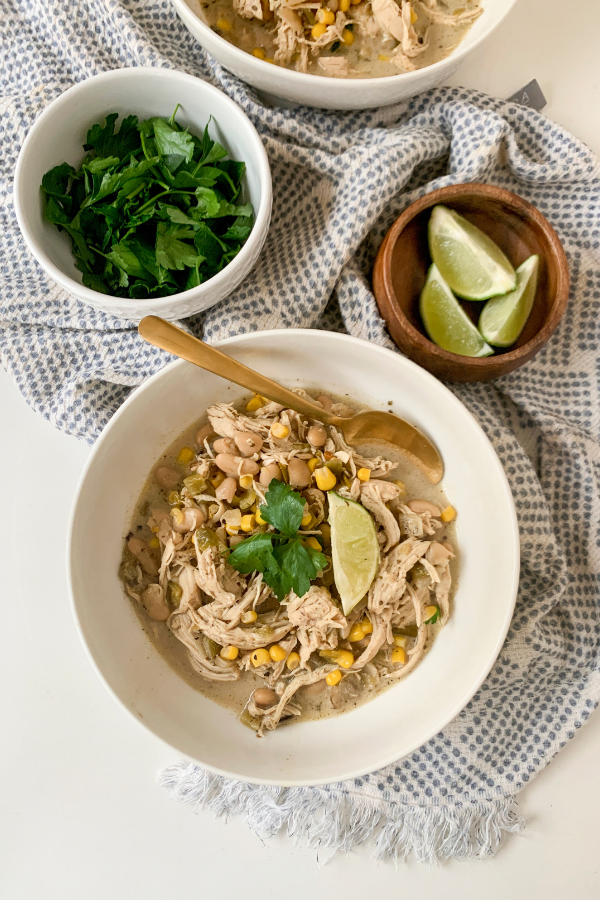 white chicken chili served in a bowl with parsley and lime